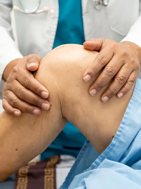 Athlete performing a controlled single-leg landing while a physical therapist watches her knee alignment