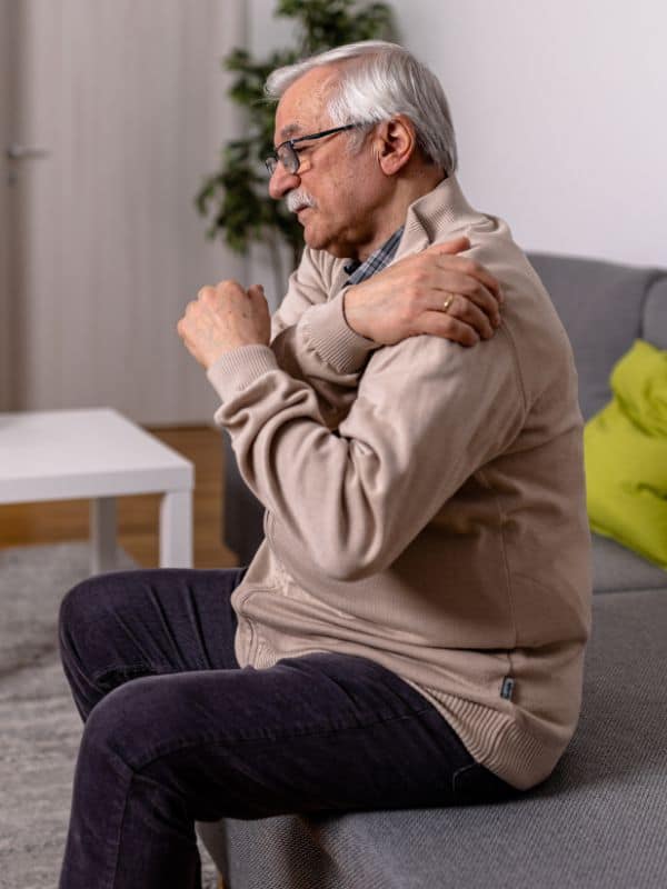 senior aged man clutching his shoulder in pain
