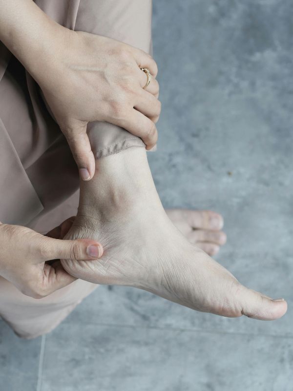 person rubbing their foot while sitting on a couch