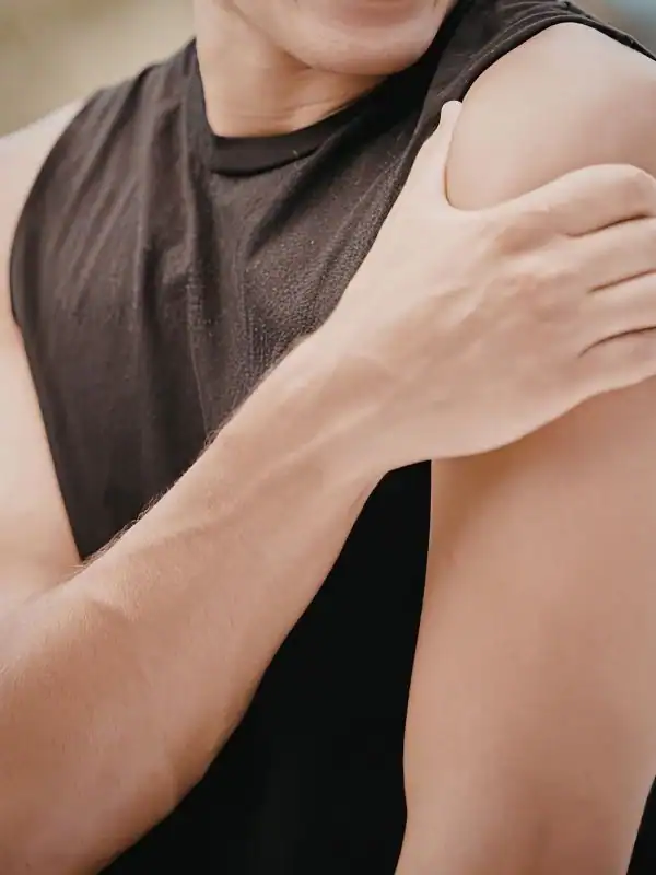 Woman struggling to reach her arm into a jacket sleeve because of a stiff shoulder