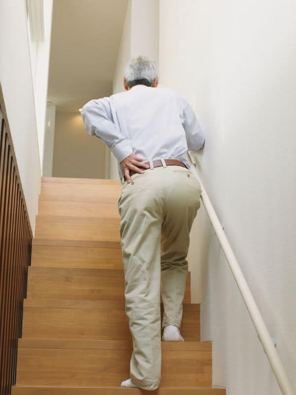 man with his hand on his side climbing stairs