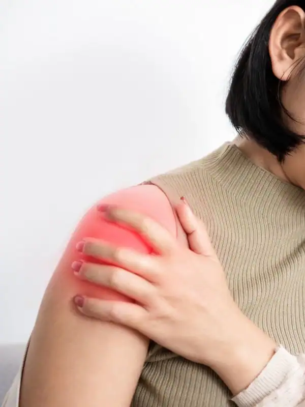 Physical therapist resistance-testing the raised arm of a middle-aged patient